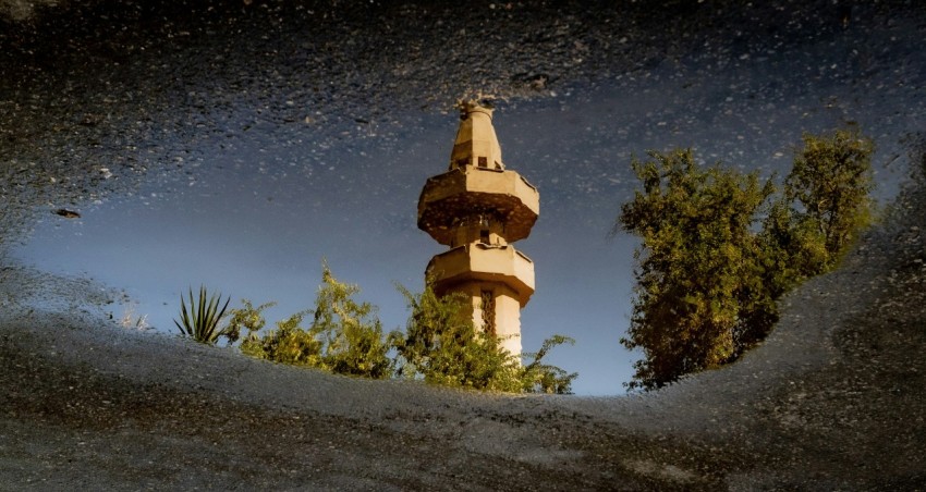 a reflection of a clock tower in a puddle of water