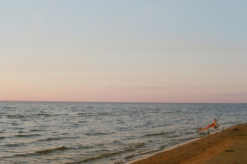 a person walking a dog on a beach at sunset