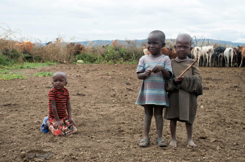 girl in gray dress holding stick standing beside boy in red and blue stripe shirt during