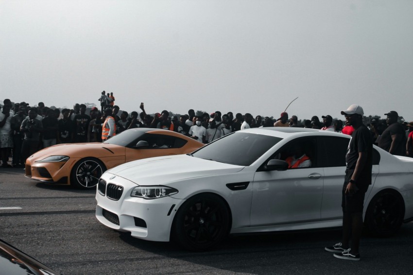 a group of people standing around a white car