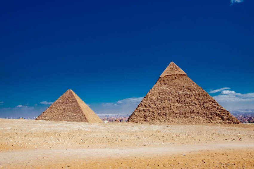 a couple of pyramids in a desert with giza pyramid complex in the background