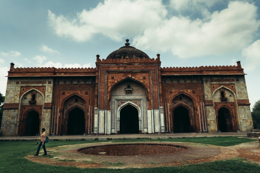 a large building with a person walking in front of it with purana qila in the background