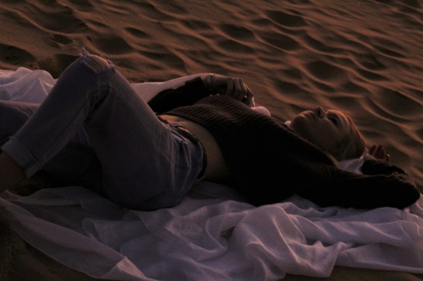 woman in black shirt lying on brown sand