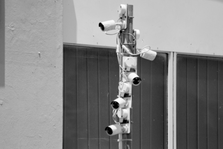 a black and white photo of security cameras on a pole d2RHg
