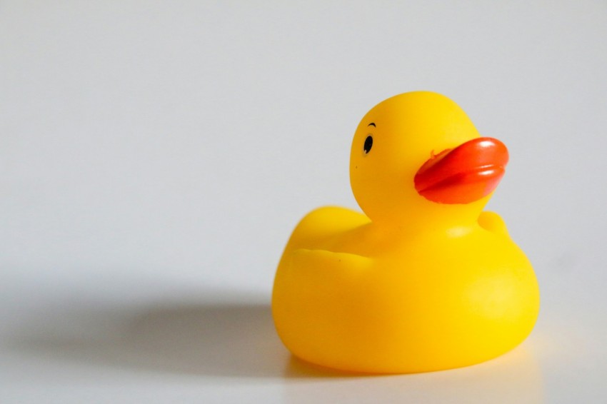 a yellow rubber ducky sitting on a white surface