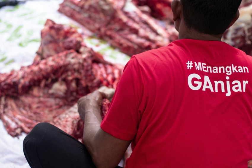 a man in a red shirt is looking at a pile of meat