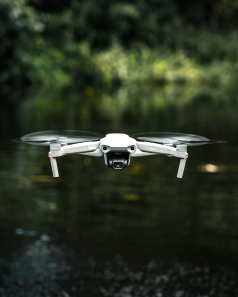 white and gray drone in mid air during daytime