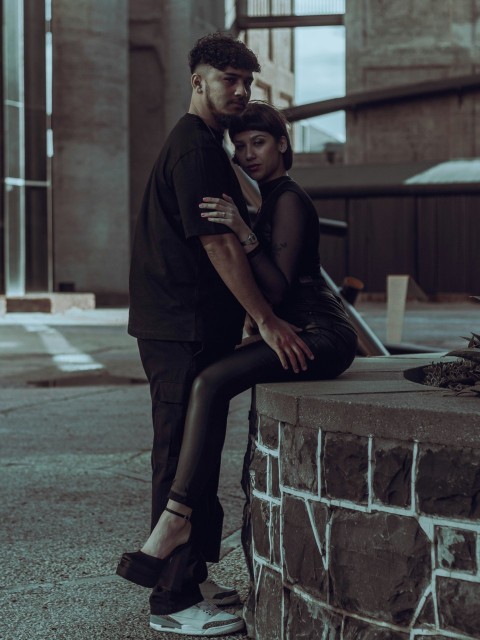a man and a woman sitting on a brick wall