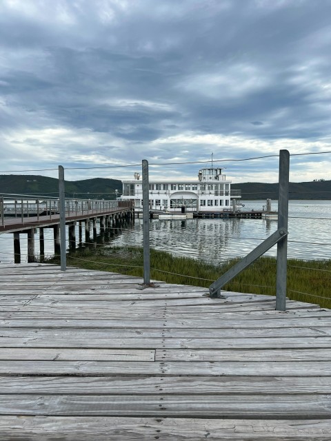a wooden dock with a large white building in the background Tl602zjXb