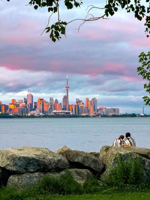 a couple of people sitting on top of a large rock