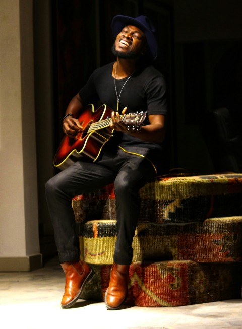 man in black long sleeve shirt and blue denim jeans playing brown acoustic guitar