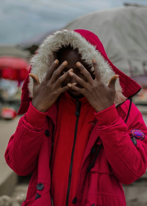 person in red and white fur hoodie covering face with hand 4C8P4GZY