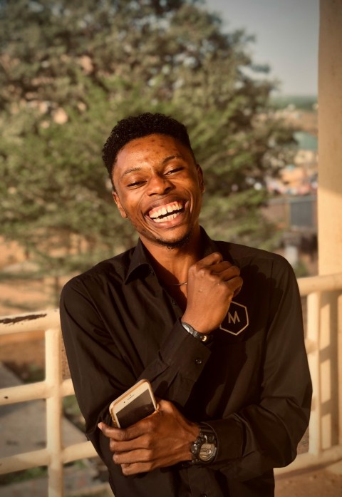 a man smiling while holding a cell phone 0Ftgn7