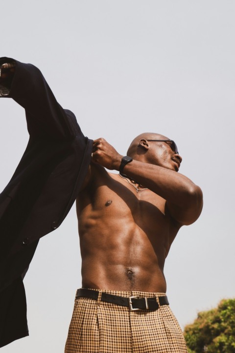 a man with no shirt is holding a jacket uRnjI3Nj