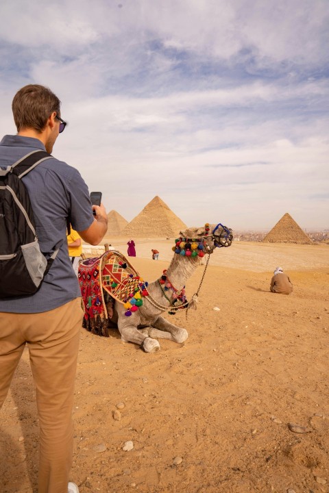 a man standing next to a camel in the desert