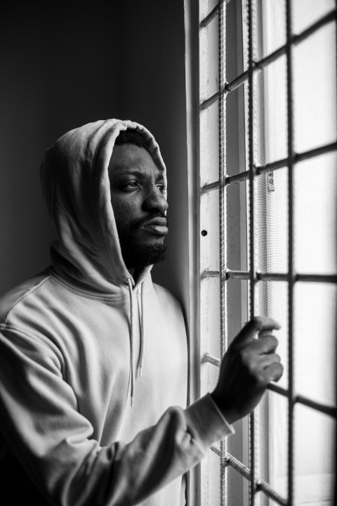 man in white hoodie standing near window