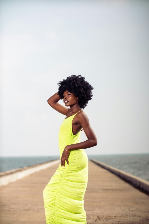 a woman in a yellow dress standing on a pier