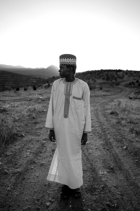 a man wearing a white robe and standing on a dirt road