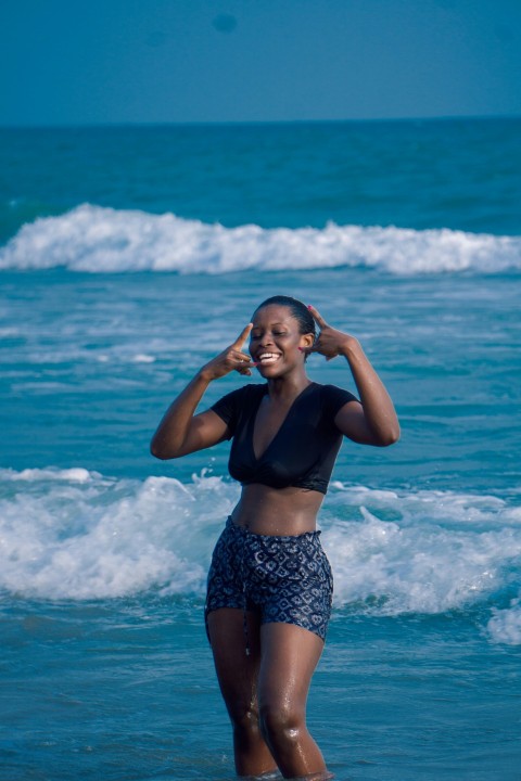 woman in black sports bra and blue and white shorts standing on beach during daytime