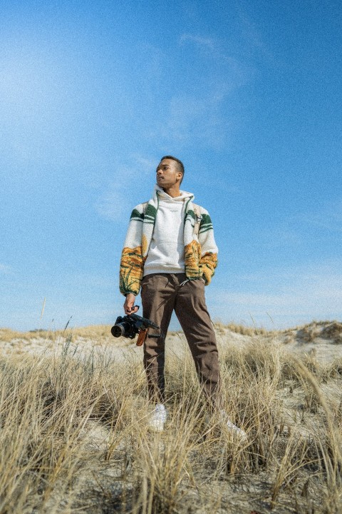 a man standing in a field holding a camera